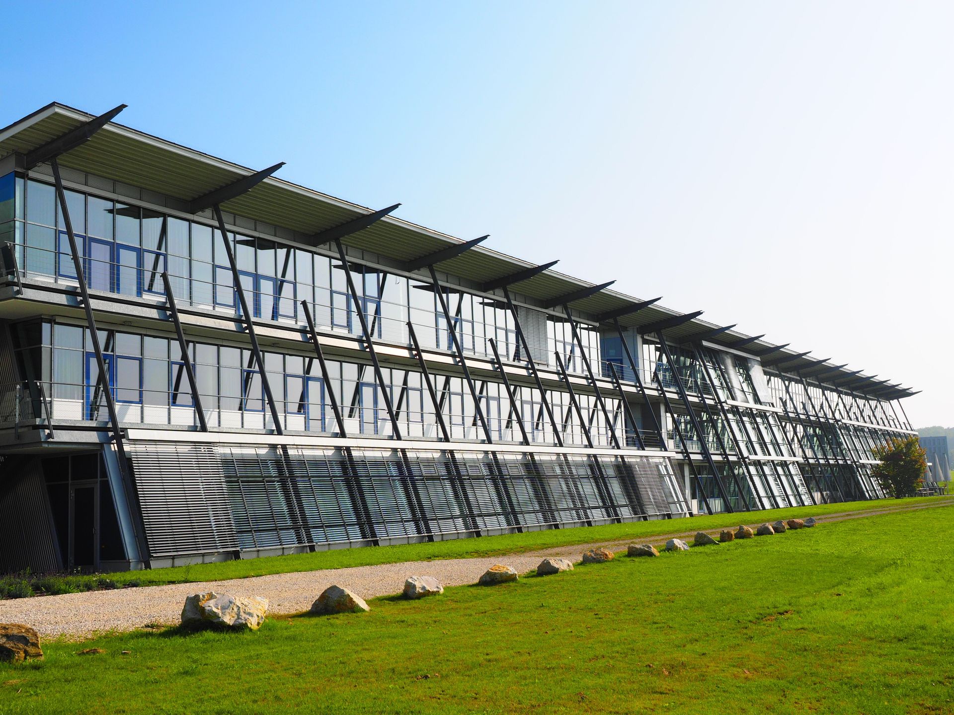 Sleek modern architecture with a glass facade and green lawn surroundings.