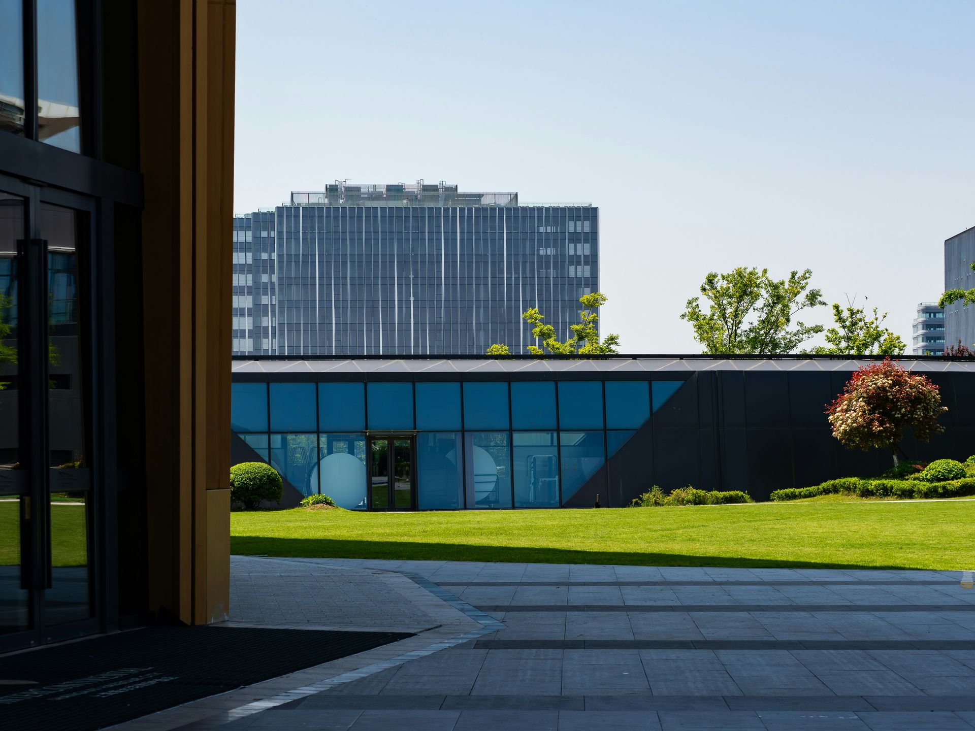 Modern office buildings with green lawn and trees.