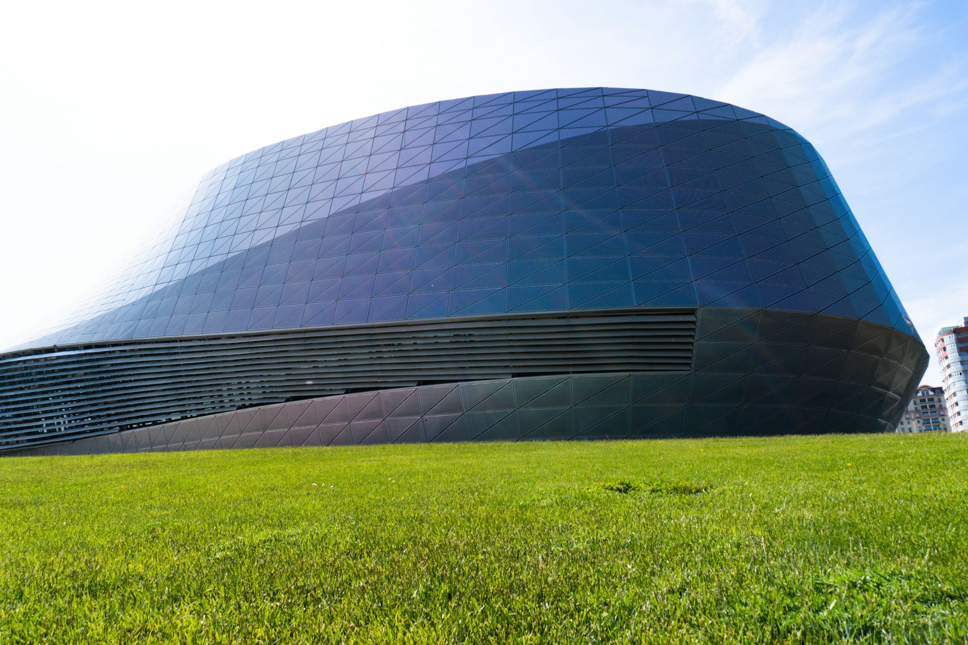 Modern curved building with green grass foreground