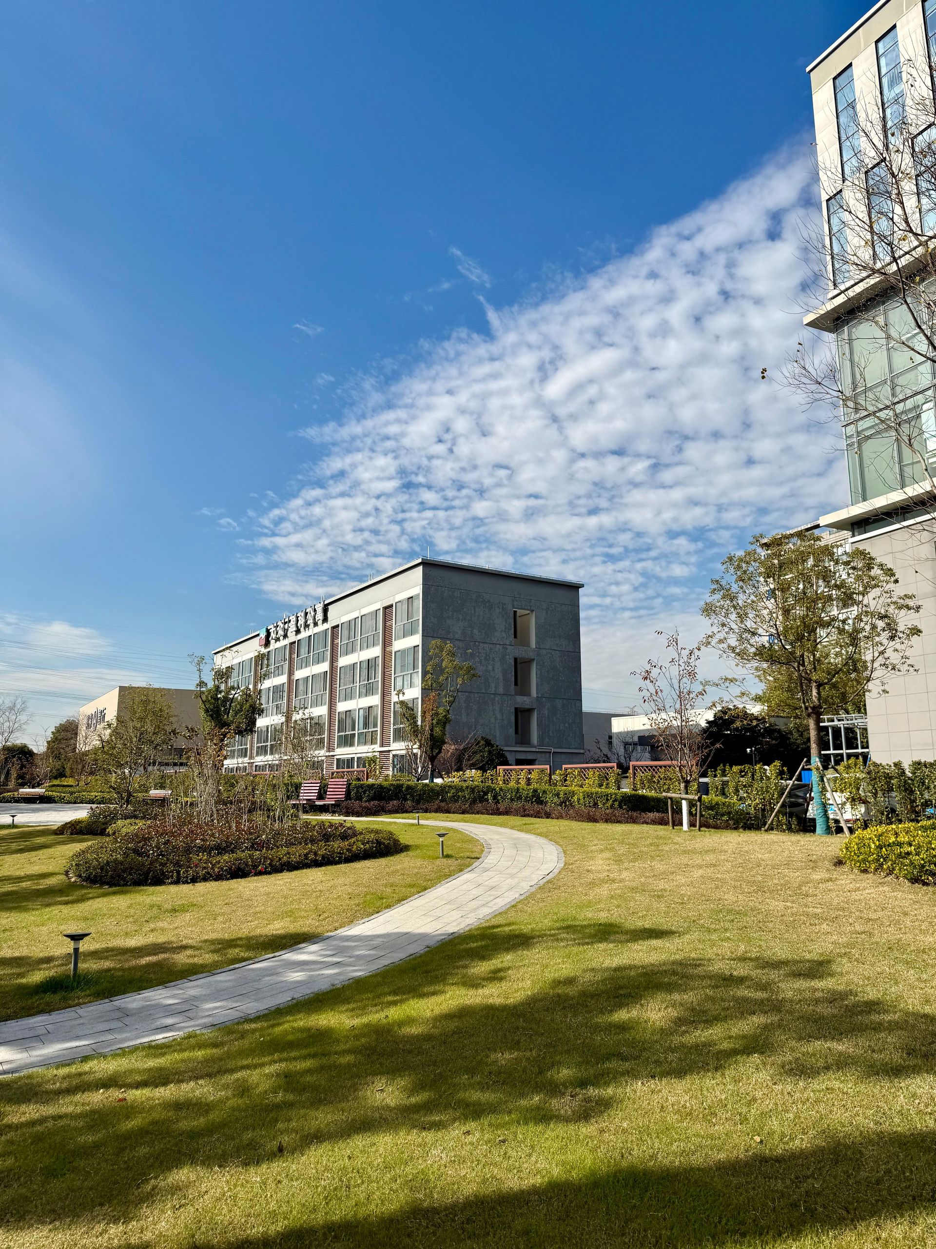 A modern office complex with green lawns and clear skies in Shanghai, showcasing urban development.