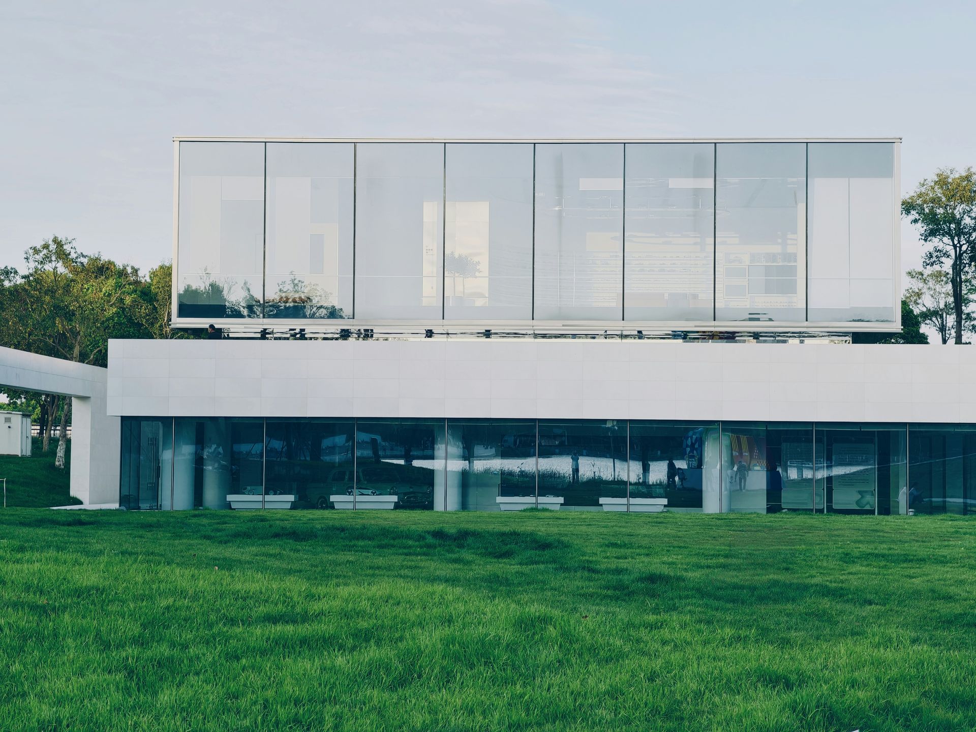 Modern white building with large glass windows and green lawn